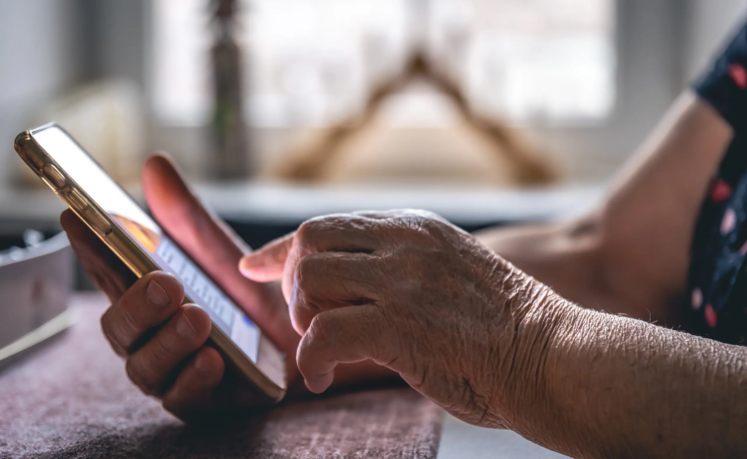 Hände eines älteren Menschen, die ein Handy halten